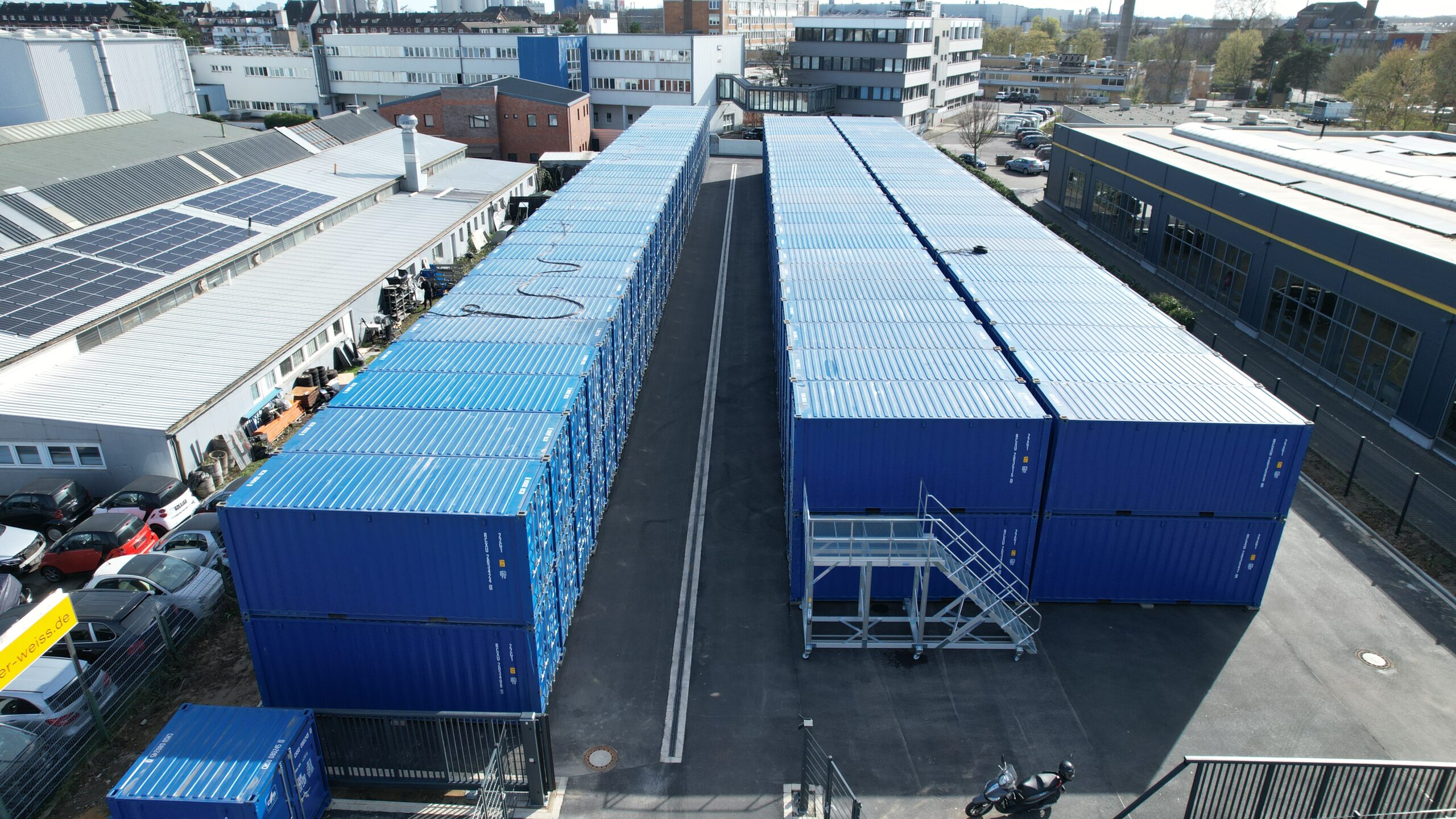 Luftaufnahme LAGER KING Neuss: zwei Reihen blauer Lagercontainer auf zwei Ebenen mit breiter Zufahrt und mobiler Treppe